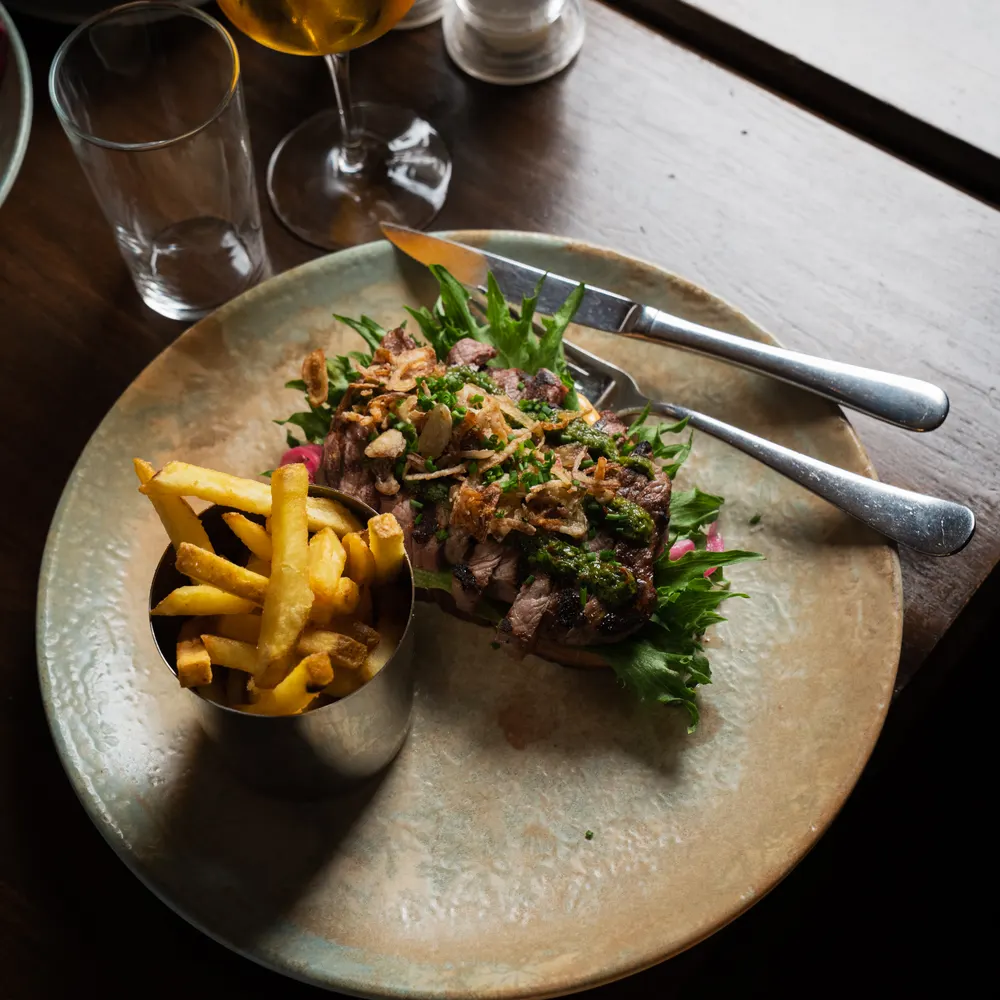 Skivad biff med örtsås och pommes på tallrik